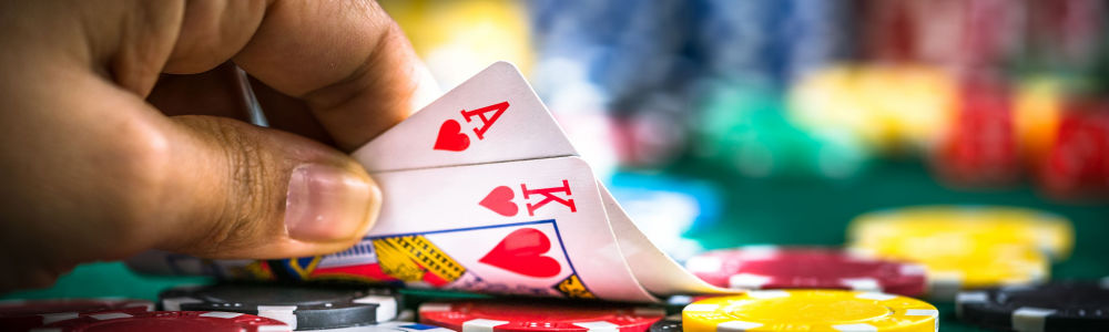 Player showing us the A and K of Hearts on a poker table with chips ready to play