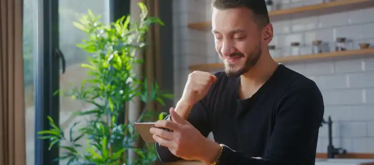 man holding a smartphone and pumping his hand in victory