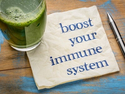 a green healthy drink sitting on a table with a pad of paper with Boost Your Immune System