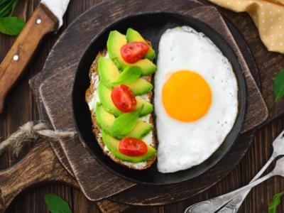 breakfast foods - fried egg and avocado sandwiches on a frying pan served on a table  