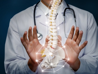 a chiropractor holding his hands out on an image of a spine in front of him