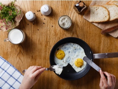 eggs in a pan on a table with seasonings, toast and breakfast items