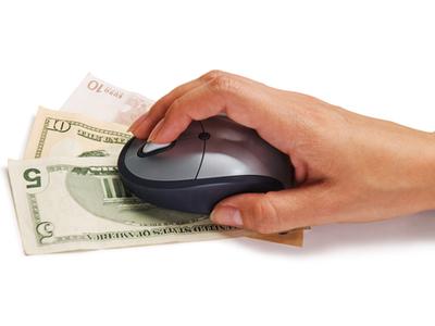 hand on a computer mouse which is on cash bills