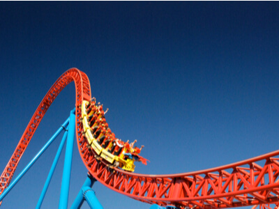 people riding an orange and yellow roller coaster in an amusement park