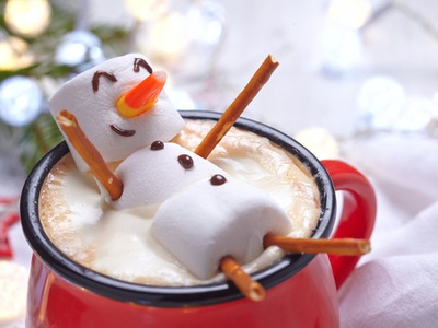 mug of hot chocolate with a marshmallow snowman floating on his back in the mug 