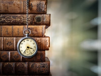 pocket watch next to a stack of old books