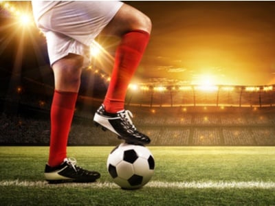soccer player with his foot on the soccer ball in a big lit up stadium