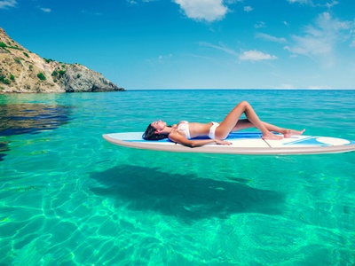 young woman floating on an air mattress in the water at a beautiful beach