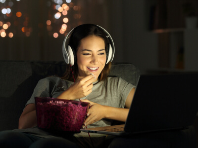woman with a bowl of popcorn watching a movie online 