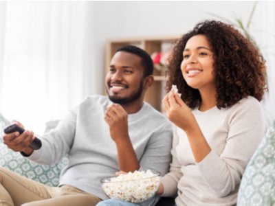 young couple watching TV together with a bowl of popcorn